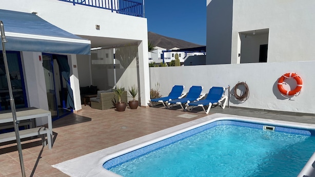 Una piscina amb rajoles blaves, envoltada de gandules i plantes en testos.