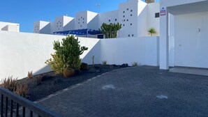 Un edifici modern amb parets blanques i un terrat pla. Als primers plans hi ha cactus i altres plantes.