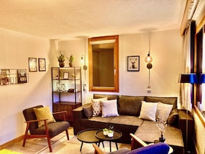 A living room with a sofa, armchairs, a coffee table, and a bookshelf.