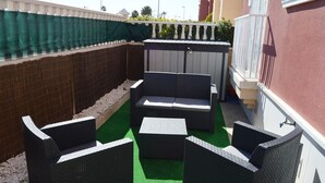 An outdoor seating area with a sofa and chairs, a small table, and a green artificial turf floor. - 2 bed ground floor Puerto marina (Los Alcázares)