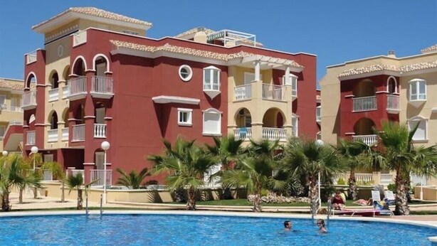 A hotel with a swimming pool surrounded by palm trees and a clear blue sky. - 2 bed ground floor Puerto marina (Los Alcázares)