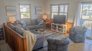 Una sala de estar con un sofá, sillones, una mesa de centro, un televisor y una estantería.