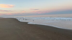 Una platja amb empremtes que condueixen a l'aigua, un mar tranquil i un cel serè.