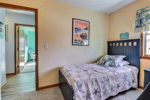 Ein Schlafzimmer mit einem Bett, einem gerahmten Bild an der Wand und einem Fenster mit Vorhängen.