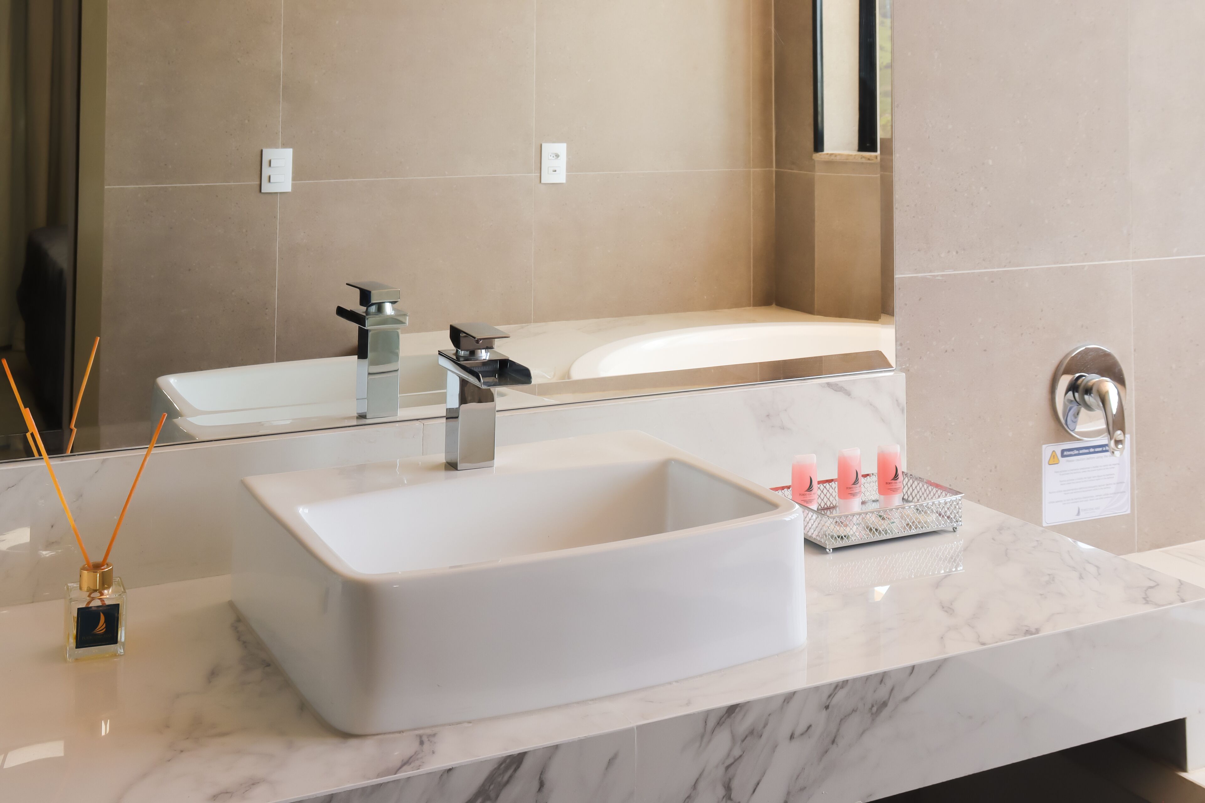 A modern bathroom with a large white sink, a mirror, and a bathtub.