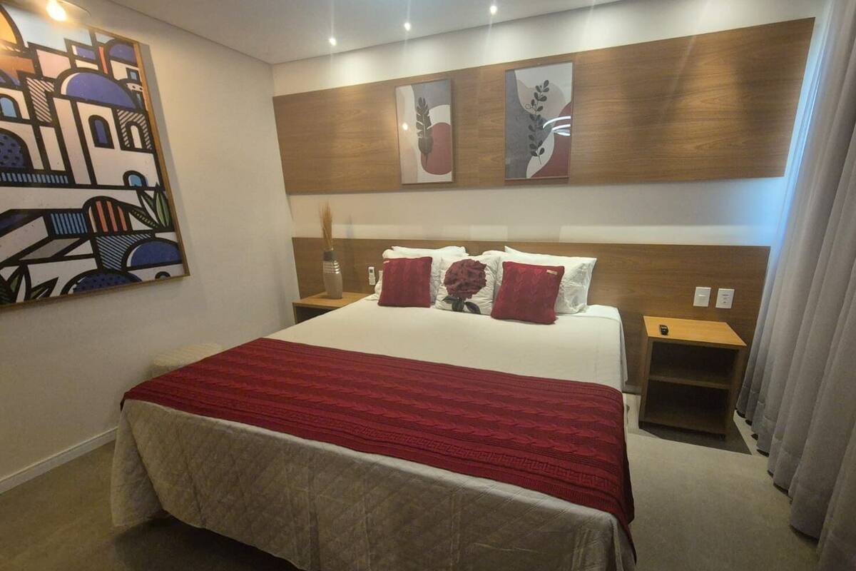 A hotel room with a large bed, a wooden headboard, and artwork on the walls.