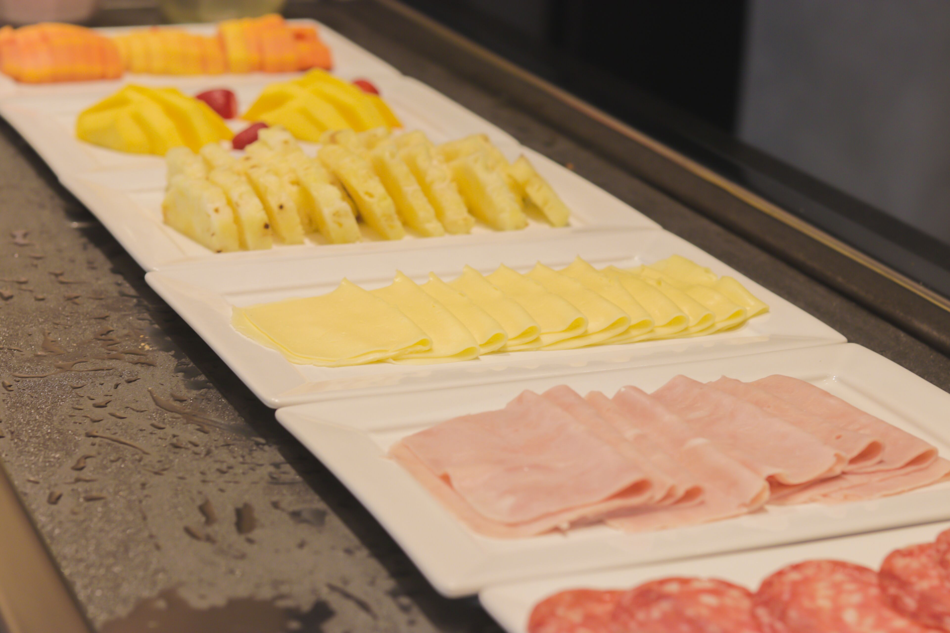 Un bufé con frutas y carnes cortadas.
