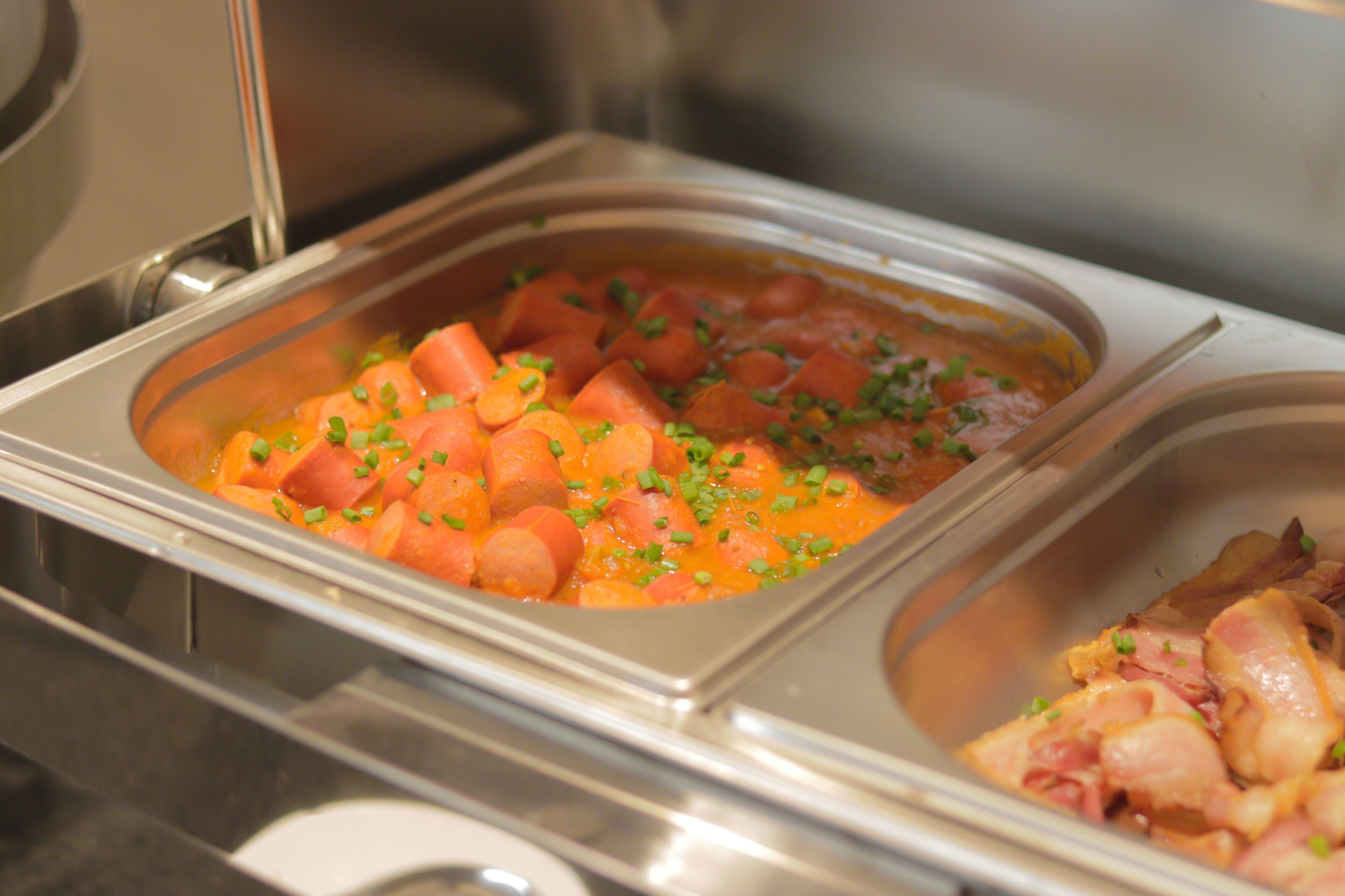 A buffet with various food items, including a section with diced vegetables and another with sliced meats.