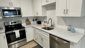 Una cocina moderna con armarios blancos, electrodomésticos de acero inoxidable y una alfombra gris.