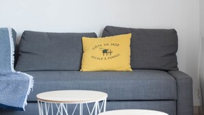 A grey sofa with a yellow pillow, a round white table, and a blue and white woven chair. - La Marine - Jardin - Golf (Pornic)