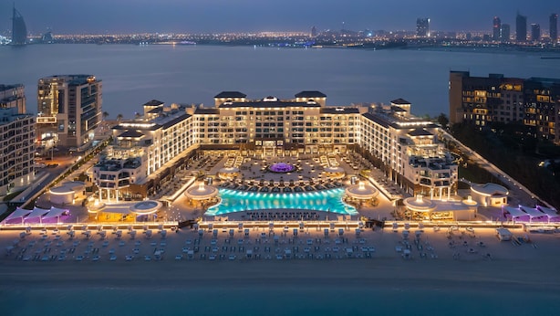 A large hotel with a central swimming pool, multiple balconies, and a beach area with sun loungers. - Taj Exotica Resort & Spa, The Palm, Dubai (Dubai)
