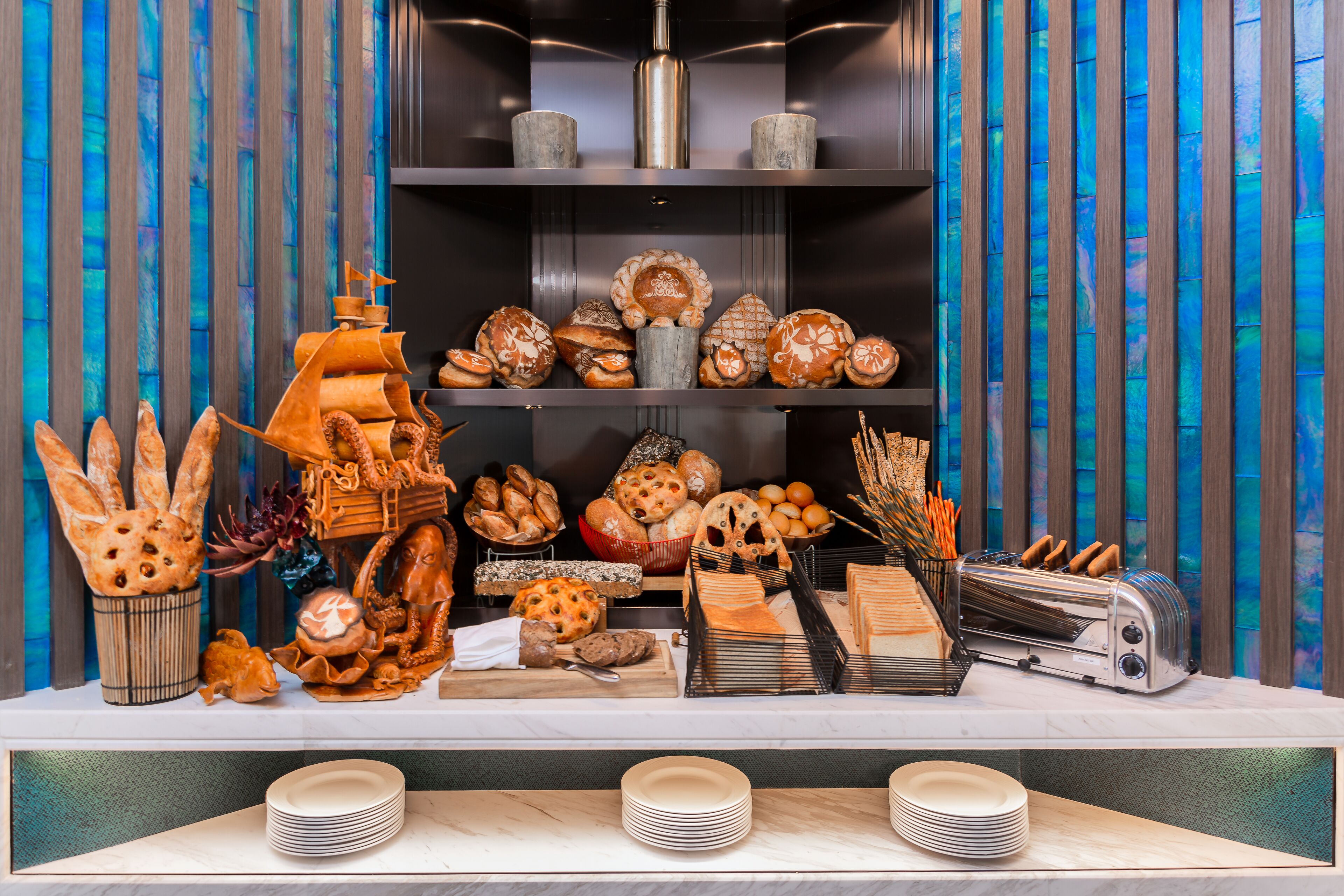 A buffet with various breads, pastries, and a toaster.