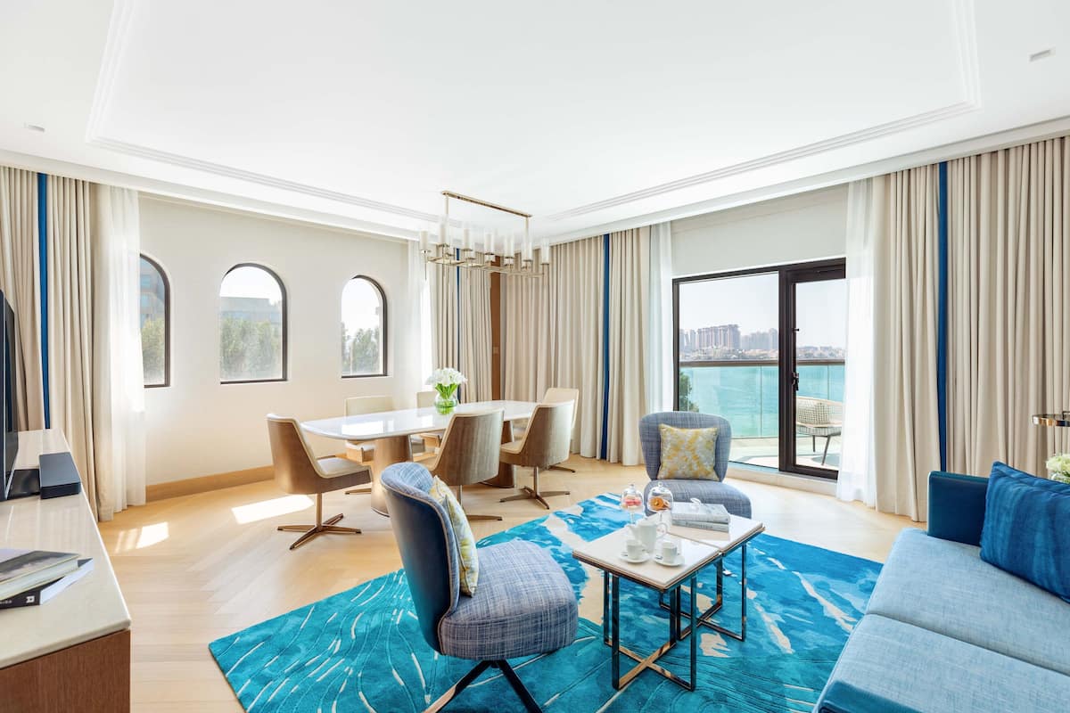 A spacious living area with a large window, a dining table, and comfortable seating.