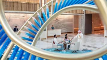 A modern lobby with a central seating area, a reception desk, and a decorative spiral structure.