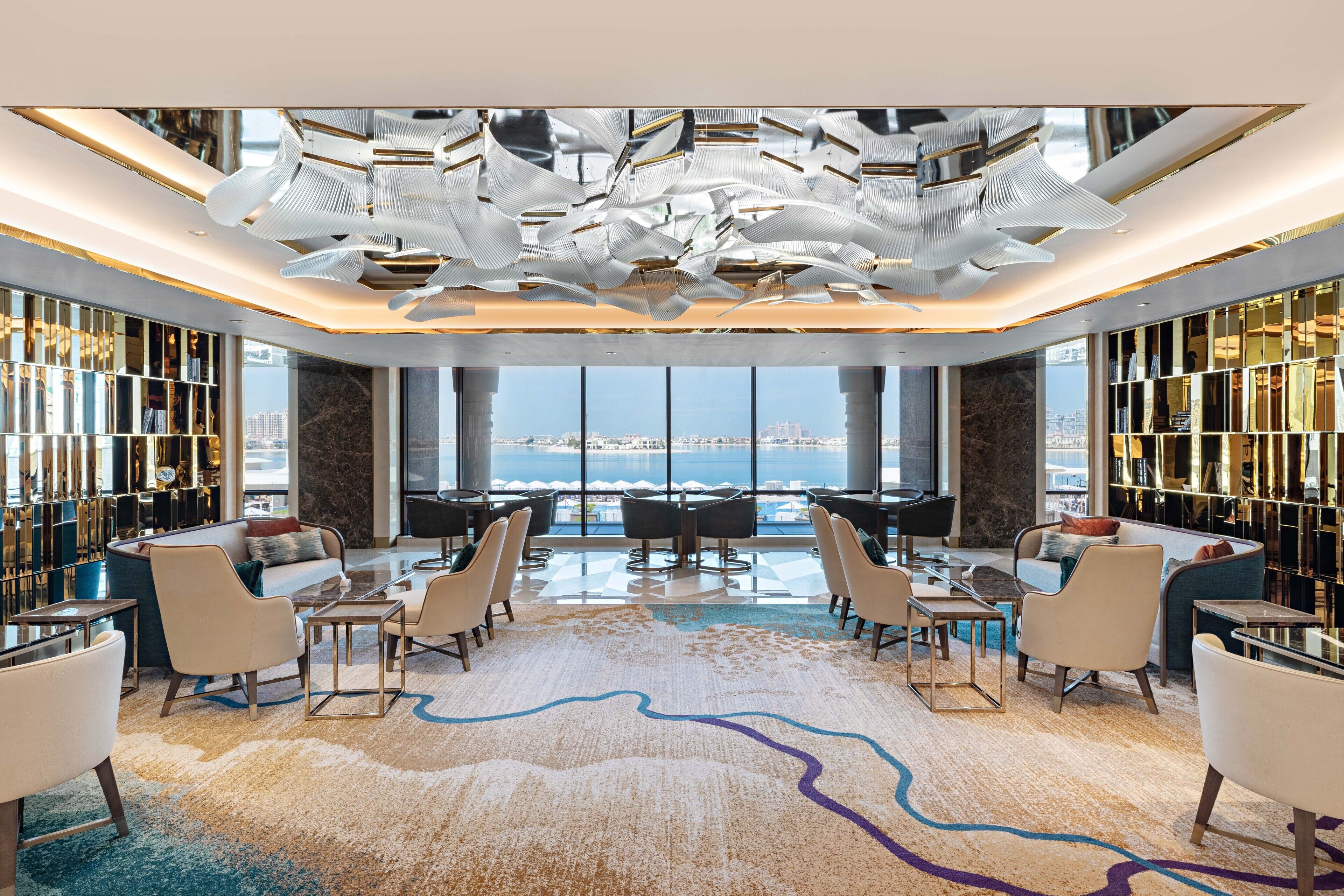 A spacious lobby with a high ceiling, modern furniture, and a large window offering a city view.