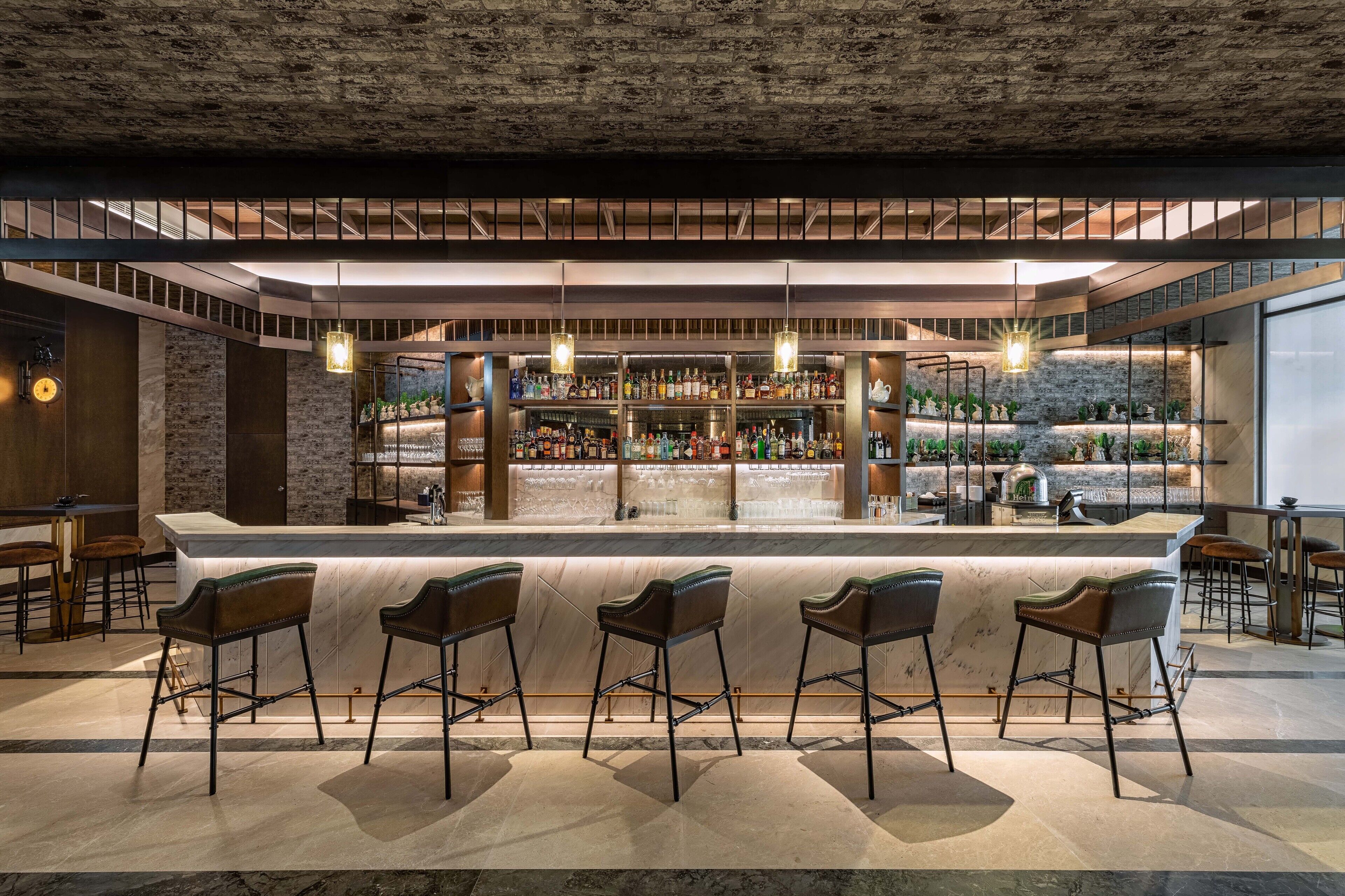 A bar area with a marble countertop, multiple stools, and a variety of bottles on shelves.