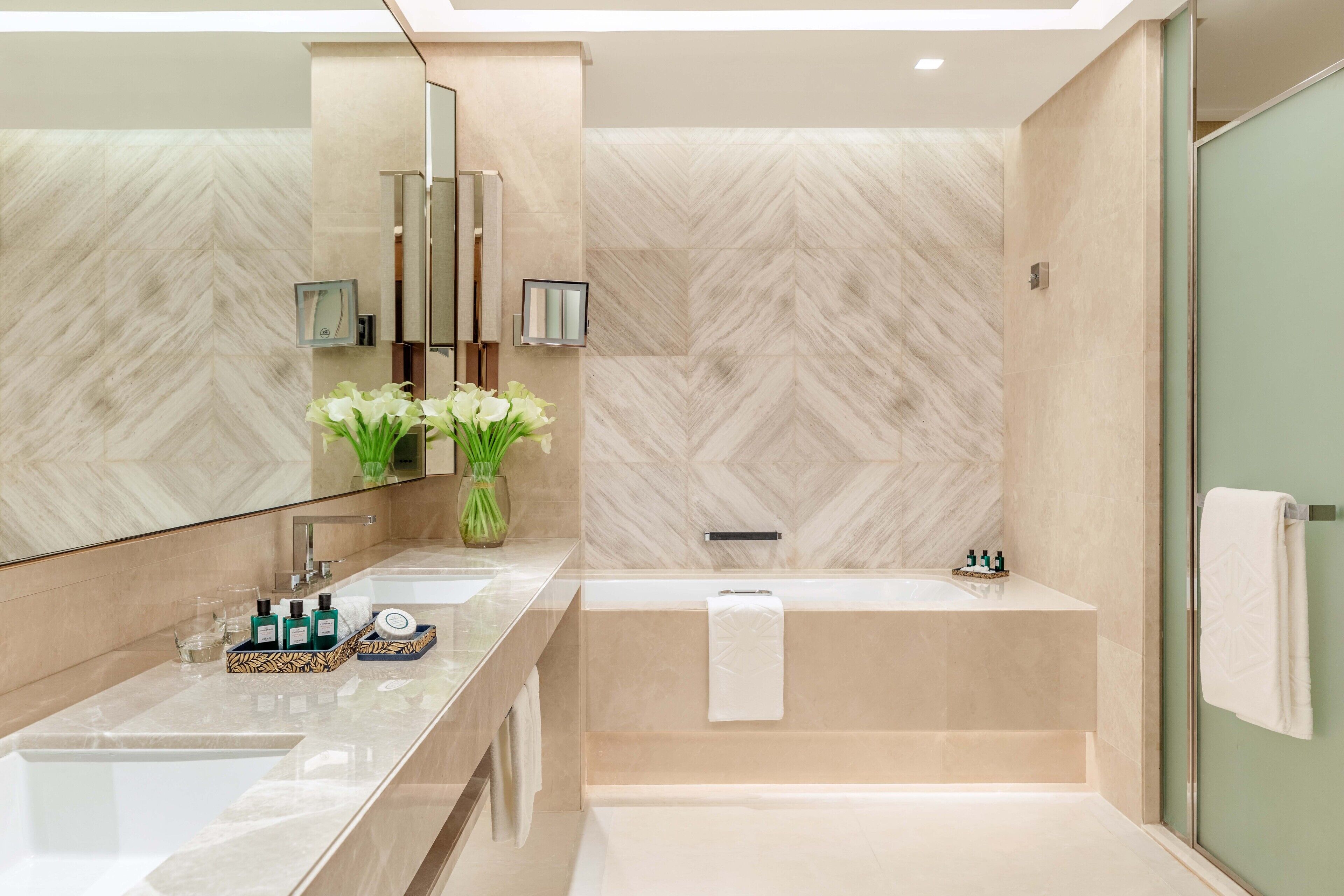 Un baño moderno con un espejo grande, una bañera y un tocador con artículos de aseo.