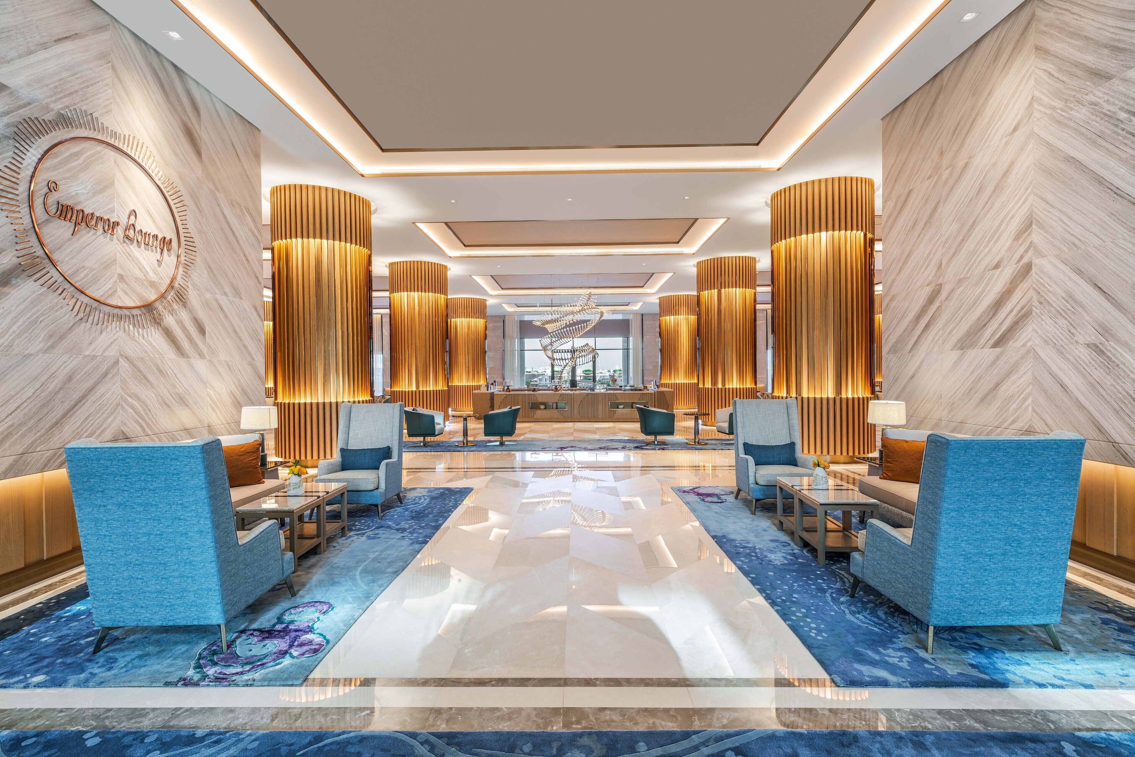 Eine moderne Lobby mit einer zentralen Sitzecke, einem Empfangsbereich und einem großen Fenster.