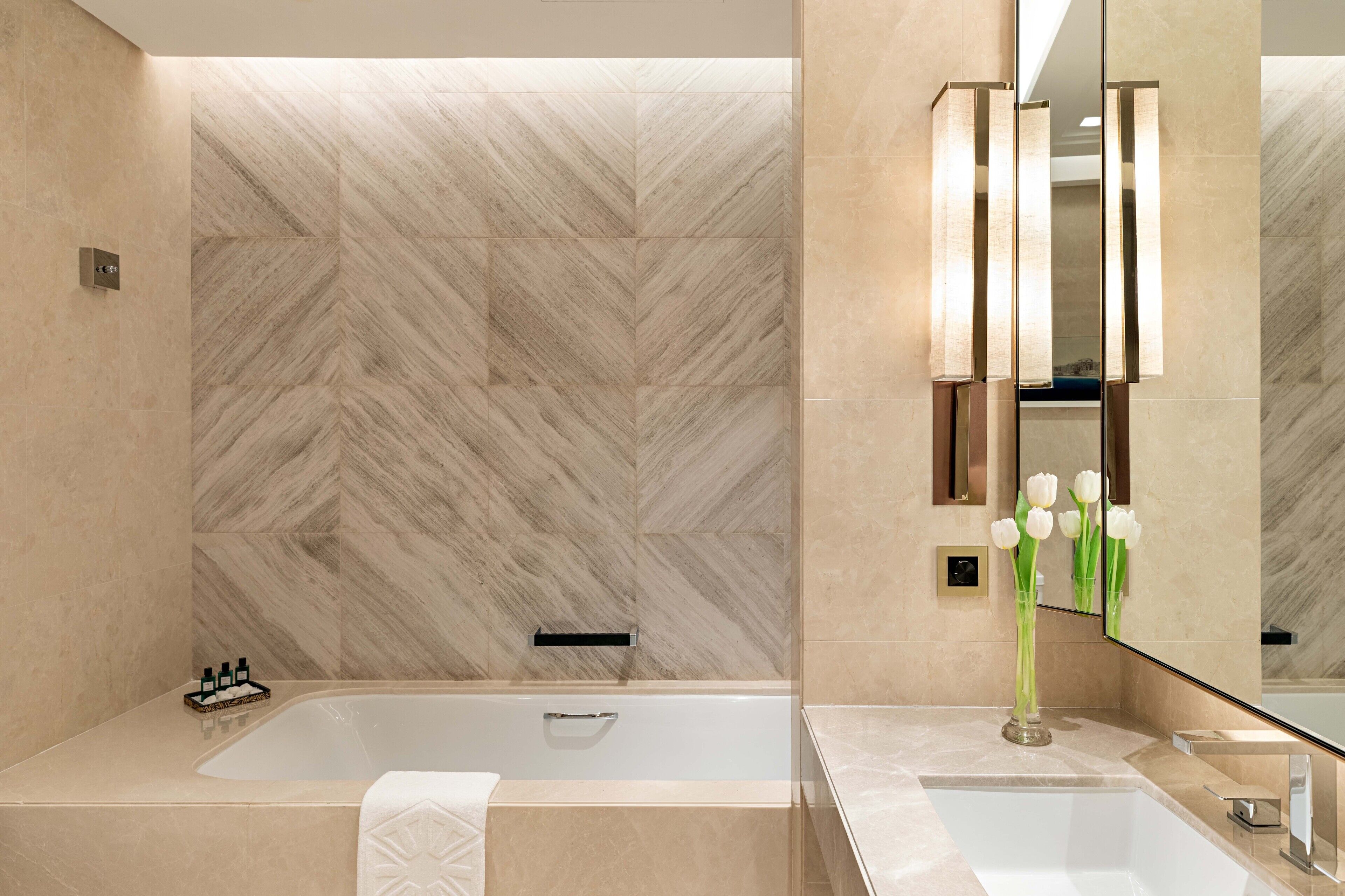 A modern bathroom with a large bathtub, a sink, and a mirror.