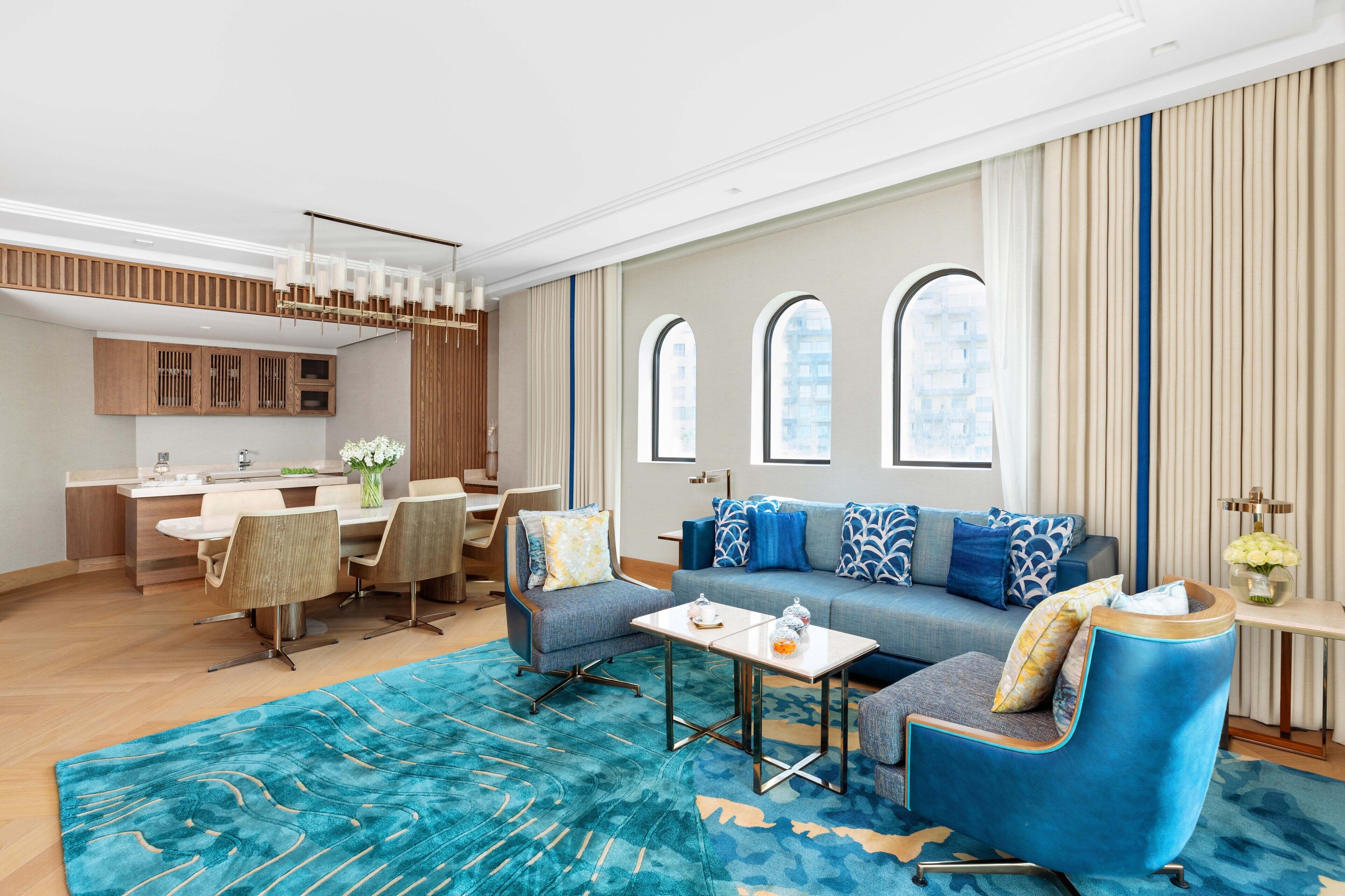 A modern living room with a sofa, chairs, a coffee table, and a dining area with a table and chairs.