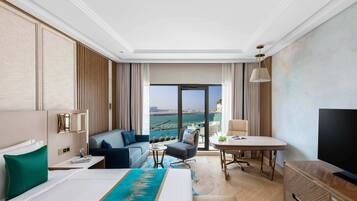 Ein Hotelzimmer mit Bett, Sofa, Schreibtisch, Fernseher und Meerblick.