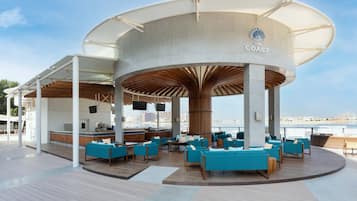 A covered outdoor seating area with blue sofas and a bar.