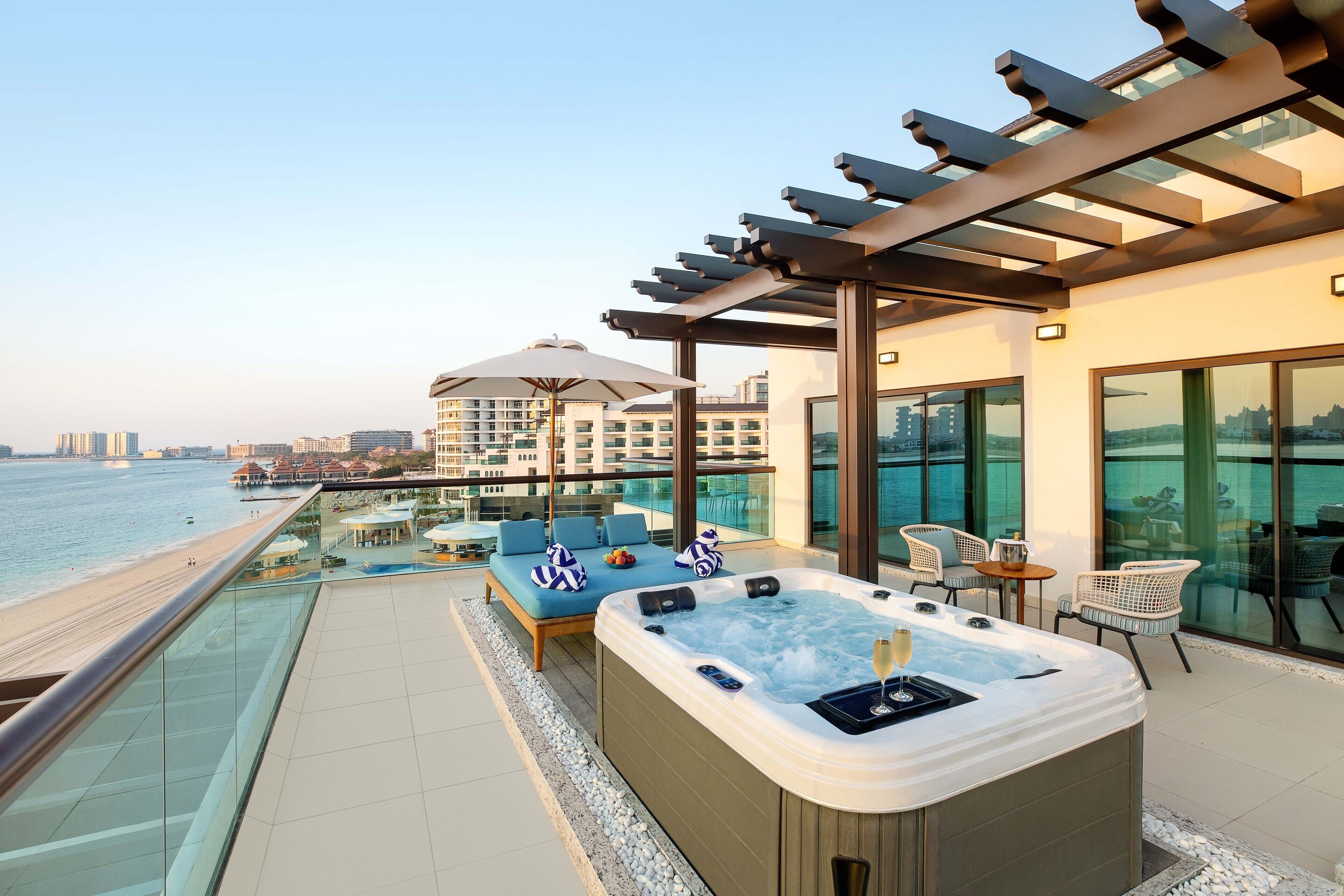 A rooftop terrace with a hot tub, lounge chairs, and a view of the sea.