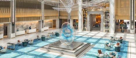 A spacious lobby with a central fountain, seating areas, and a high ceiling with unique lighting fixtures.