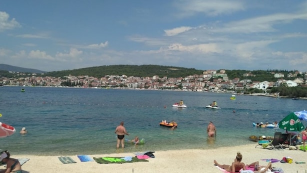 A beach with clear water, people swimming and sunbathing, and a cityscape in the background. - Apartment in Okrug Gornji with Terrace, Air condition, WIFI, Washing machine (5070-1) (Okrug Gornji)