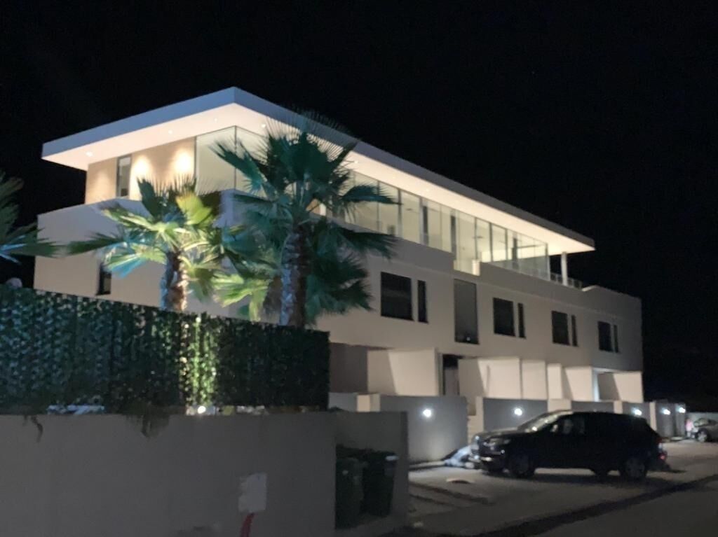 A modern two-story building with a flat roof, large windows, and a well-lit facade.