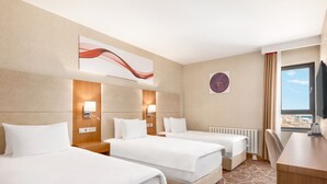 A hotel room with three single beds, a desk, and a television. - Ramada by Wyndham Elbistan (Elbistan)