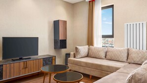 A modern living room with a flat-screen TV, a sofa, and a small coffee table. - Ramada by Wyndham Elbistan (Elbistan)