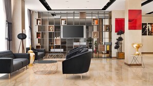 A modern living room with a large flat-screen TV, black sofas, a coffee table, and a decorative trophy on a pedestal. - Ramada by Wyndham Elbistan (Elbistan)