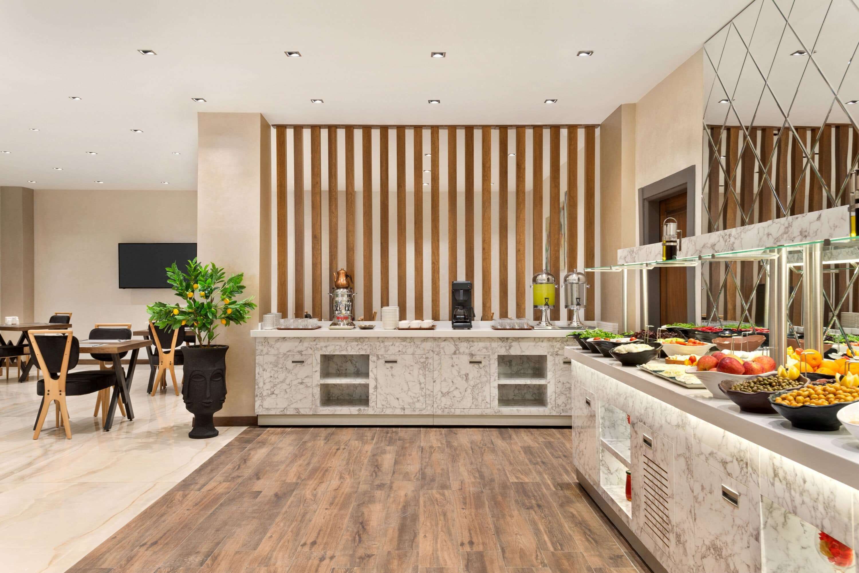 A modern hotel dining area with a buffet, wooden paneling, and a marble countertop.