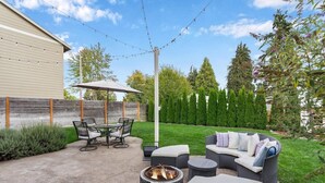 Un patio al aire libre con una chimenea, asientos e iluminación con guirnaldas.