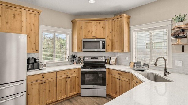 Una cocina moderna con armarios de madera, electrodomésticos de acero inoxidable y un amplio ventanal que proporciona luz natural.