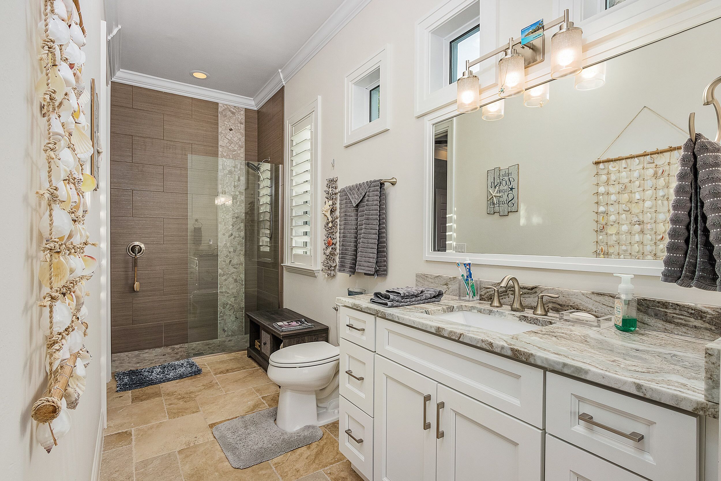 A bathroom with a glass shower, a toilet, a sink with a mirror, and a towel rack.