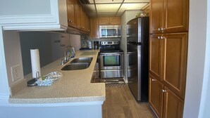 Eine Küche mit Holzausstattung, Edelstahlgeräten, einer Mikrowelle und einem Kühlschrank.