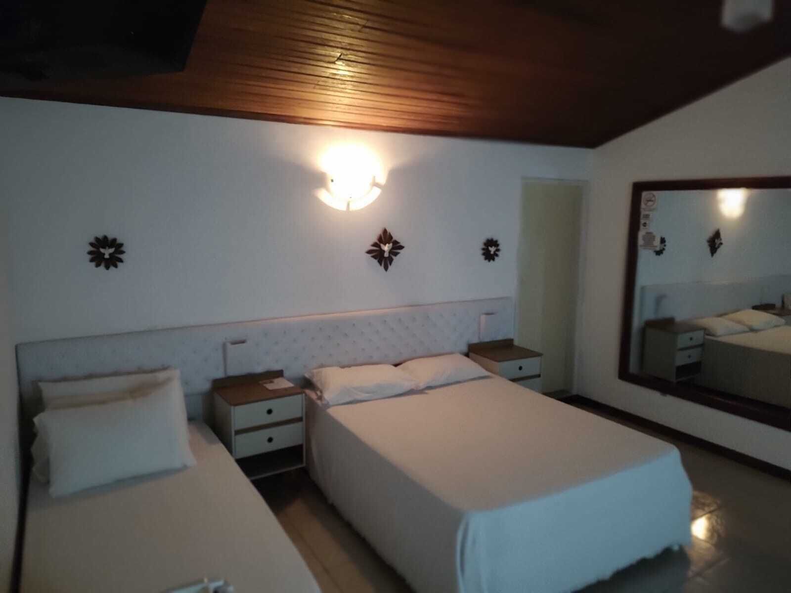 Un dormitorio con dos camas, un espejo grande y apliques en la pared.