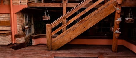 Una escalera de madera que lleva a un nivel superior, una piscina pequeña y plantas en macetas.