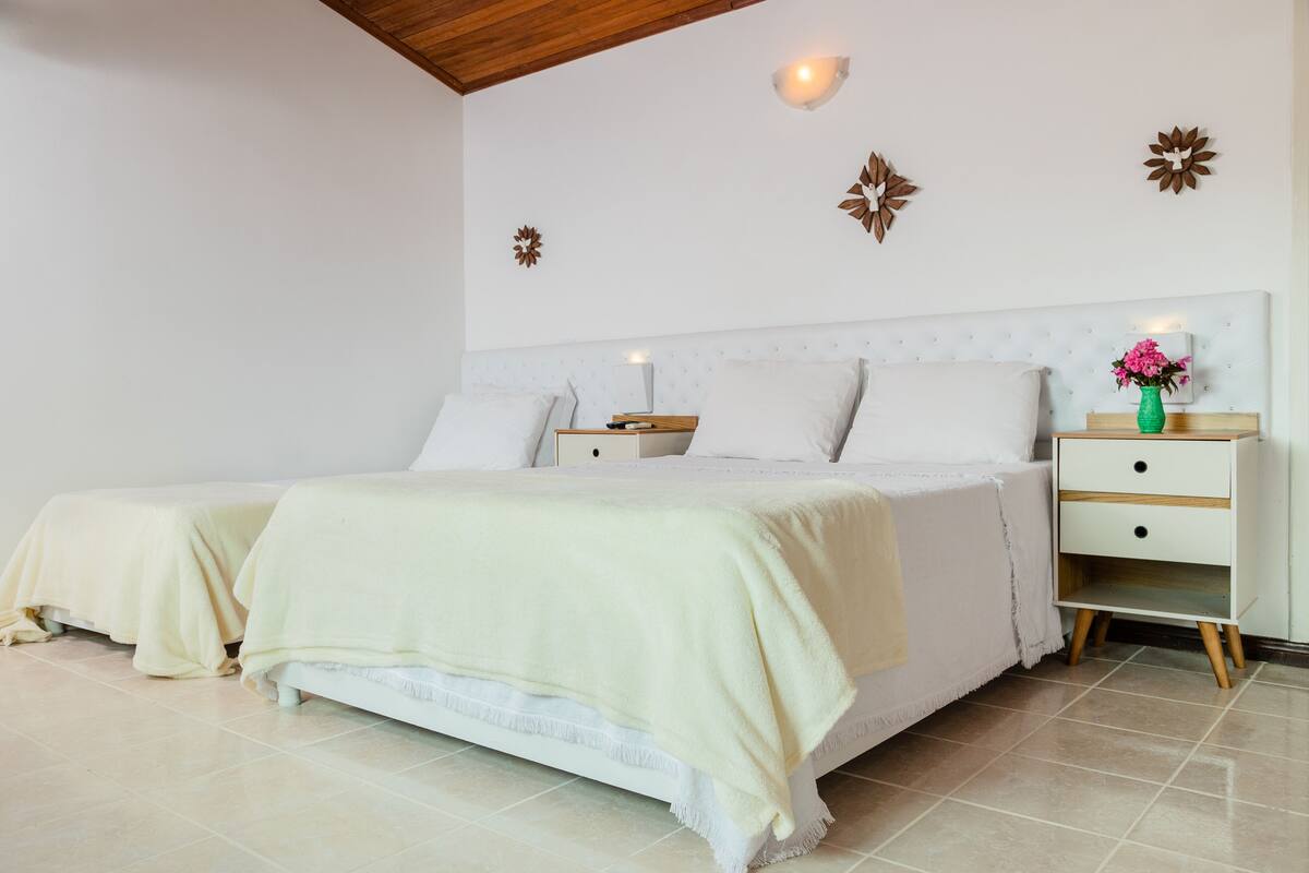 Une chambre à coucher avec un grand lit, des tables de chevet et des œuvres d’art décoratives au mur.