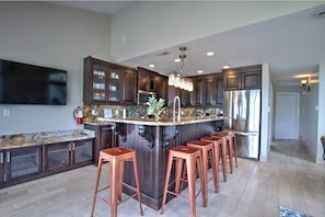 A modern kitchen with dark wood cabinets, a granite countertop, a stainless steel refrigerator, and copper bar stools. - Spinnaker Point #1 - Why rent near the beach in Bear Lake when you can rent ON the beach!? (Garden City)