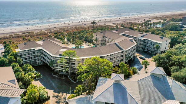 Ein Strandhotel mit mehreren Gebäuden, einem Pool und Blick auf den Strand.