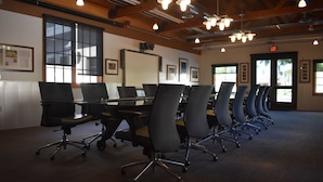 A conference room with rows of chairs and tables, large windows, and an exit sign. - Thunderbird Executive Inn and Conference Center (Glendale)