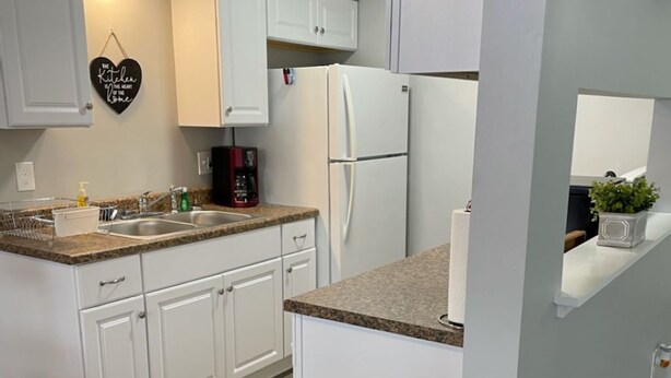 A modern kitchen with white cabinets, granite countertops, a stainless steel trash bin, and a coffee maker. - Adventure Acres- Suite B2 (Holly)