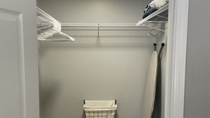 A walk-in closet with a wooden floor, a hanging laundry basket, and a ceiling light. - Adventure Acres- Suite B2 (Holly)