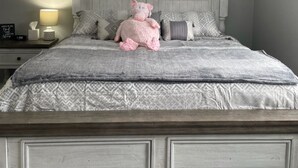 A bedroom with a bed, pillows, a nightstand, a lamp, and a stuffed toy. - Adventure Acres- Suite B2 (Holly)