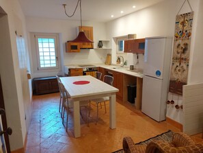 Una cocina compacta con una mesa, sillas, refrigerador y lavamanos.