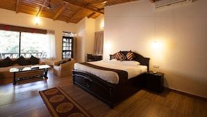 A bedroom with a wooden ceiling, a bed with pillows, a nightstand, a chair, a sofa, and a window with curtains. - Aamod @ Bhimtal (Nainital)