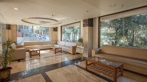 A spacious lobby with a large sofa, a coffee table, and a potted plant. - Aamod @ Bhimtal (Nainital)
